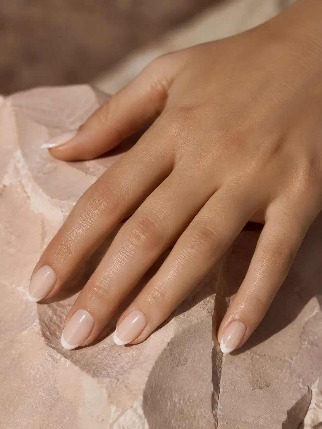 Inspiración IA de manicura nude con puntas francesas blancas sobre piedra rosa